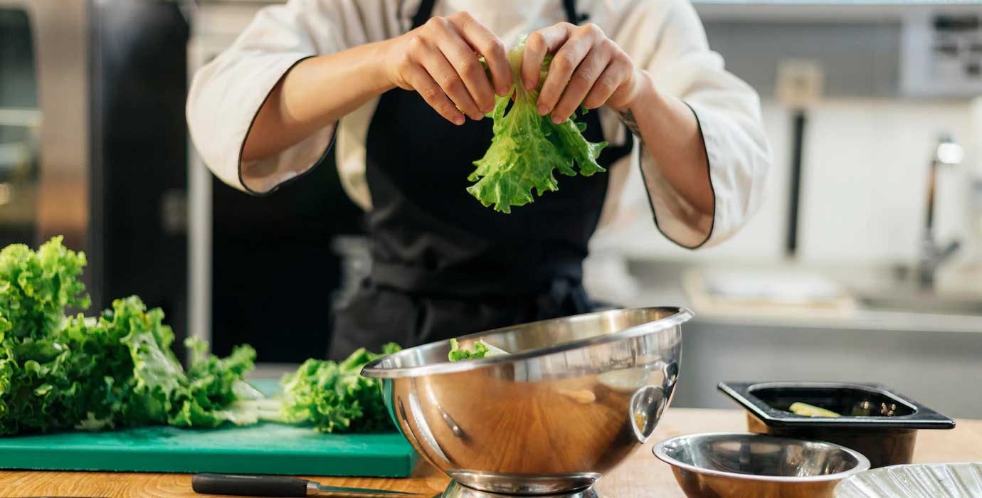 Front-View-Female-Chef-Tearing-Salad-Kitchen_23-2148763183